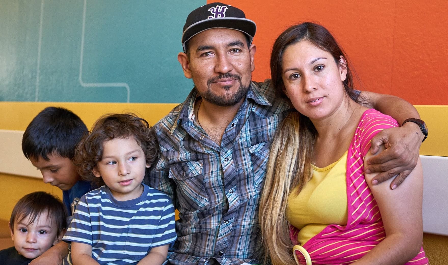 A family seated together on a bench outside an OLE health center